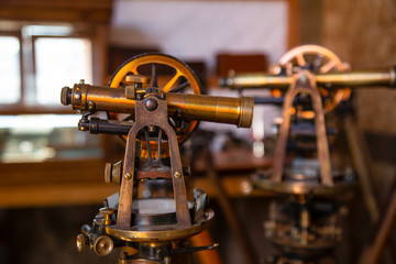 Two antique surveyors sextants on wooden tripods in workroom environment