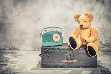 Retro radio and Teddy Bear toy sitting on old aged classic travel trunk with leather handles circa...