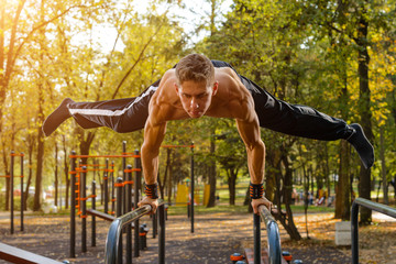 Athletic guy doing gymnastics outdoor - obrazy, fototapety, plakaty