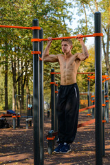Fitness man doing workouts on horizontal bar outdoors
