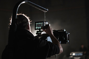 Professional videographer holding camera mounted on easy rig. Videographer using steadicam. Pro equipment helps to make high quality video without shaking.