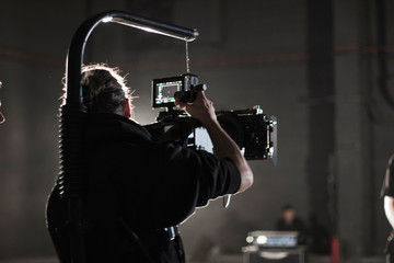 Professional videographer holding camera mounted on easy rig. Videographer using steadicam. Pro...