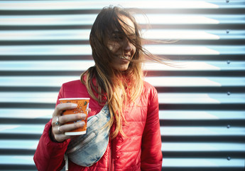 young woman in red jacket with blue jeans Waist bag drinking coffee outdoors