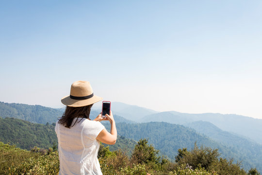 Woman taking photo from top of mountain