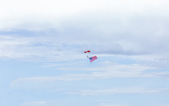 man parachuting high in the sky carrying american flag - Powered by Adobe