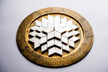 Kaju Katli is a Diamond shape Indian sweet made using cashew sugar and mava, served in a plate or bowl over moody background. selective focus