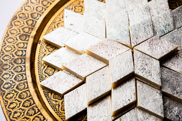 Kaju Katli is a Diamond shape Indian sweet made using cashew sugar and mava, served in a plate or bowl over moody background. selective focus