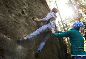 A man rock climber climbing a rock and his partner insuring.