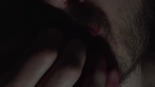 Creepy man zombie, cannibal furiously eating raw meat with frenzy. Blood drips from the mouth. Horror, halloween concept