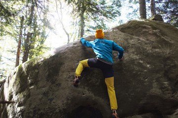 A man rock climber climbing a rock outdoors in forest