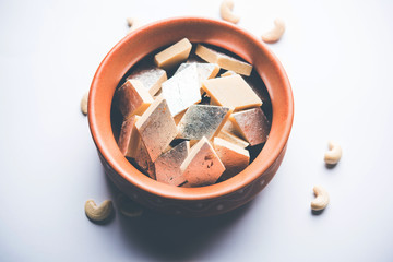 Kaju Katli is a Diamond shape Indian sweet made using cashew sugar and mava, served in a plate or bowl over moody background. selective focus