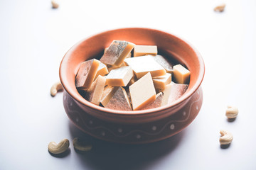 Kaju Katli is a Diamond shape Indian sweet made using cashew sugar and mava, served in a plate or bowl over moody background. selective focus