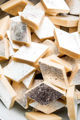 Kaju Katli is a Diamond shape Indian sweet made using cashew sugar and mava, served in a plate or bowl over moody background. selective focus