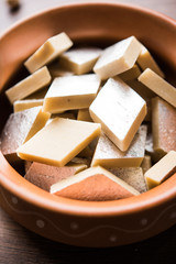 Kaju Katli is a Diamond shape Indian sweet made using cashew sugar and mava, served in a plate or bowl over moody background. selective focus