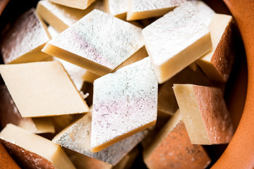 Kaju Katli is a Diamond shape Indian sweet made using cashew sugar and mava, served in a plate or bowl over moody background. selective focus