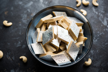 Kaju Katli is a Diamond shape Indian sweet made using cashew sugar and mava, served in a plate or bowl over moody background. selective focus