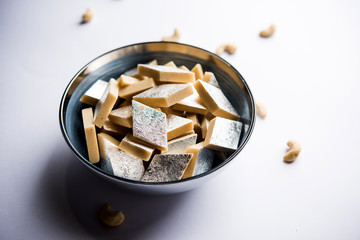 Kaju Katli is a Diamond shape Indian sweet made using cashew sugar and mava, served in a plate or bowl over moody background. selective focus