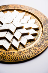 Kaju Katli is a Diamond shape Indian sweet made using cashew sugar and mava, served in a plate or bowl over moody background. selective focus