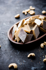 Fototapeta premium Kaju Katli is a Diamond shape Indian sweet made using cashew sugar and mava, served in a plate or bowl over moody background. selective focus