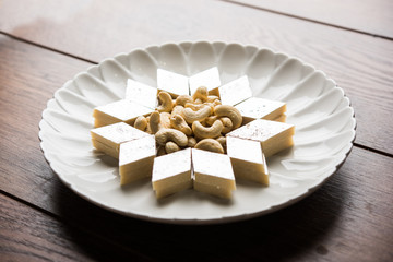 Kaju Katli is a Diamond shape Indian sweet made using cashew sugar and mava, served in a plate or bowl over moody background. selective focus
