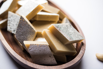 Kaju Katli is a Diamond shape Indian sweet made using cashew sugar and mava, served in a plate or bowl over moody background. selective focus