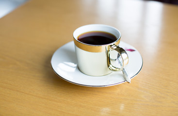 Luxury High End Gold Plated Coffee Cup on Wooden Table in Cafe. Upscale Luxury Premium Cafe Restaurant. Cup of Coffee or Tea Breakfast. Expensive Gourmet Coffee. Food and Drink. Copy Space.