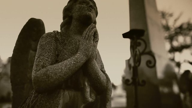 Statue of an angel praying in a cemetery.
Funeral concept.