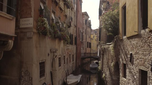Wide tilt up shot of historic water canal street Cale Castagna with brick wall, Venice, Italy
