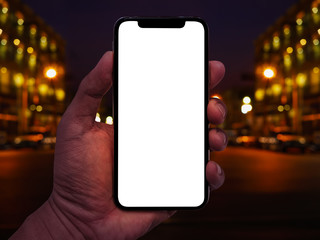 Hand holding smartphone with abstract bokeh of city night light background.