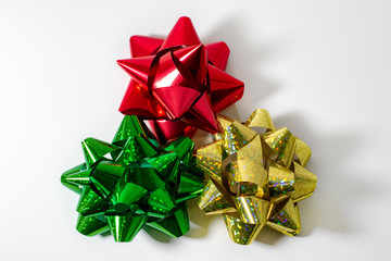 red, green and gold bows in a trio on white background top down view centered