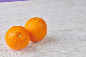 two oranges on a white wooden background