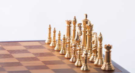 Gold and silver chess pieces on a wooden chess board