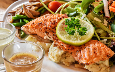 Grilled salmon steak with vegetables salad and wasabi sauce.