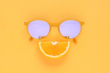 Slice orange fruit and yellow sunglasses set as smiling face on yellow background for Minimal summer concept.