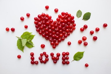 Heart made from cherries. Red cherries on white are lined with the word love. Love concept. Top view, flat lay.