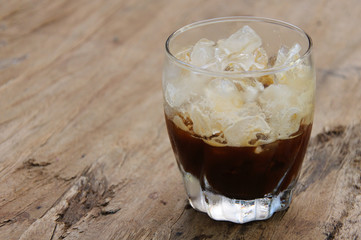 A glass of Shaken Espresso on wooden table that mixing ice cube with coffee for cold drink to enjoy hot weather of the summer. This photo has space for text and background.