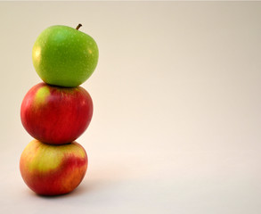 column of three colored apples on a white background
