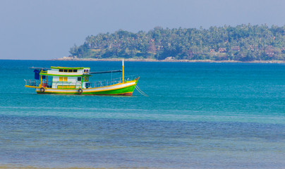 Fototapeta premium multi-colored boat moored at the shore floats on the sea