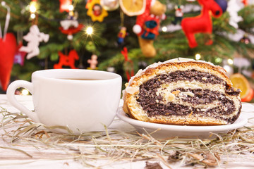 Poppy seeds cake, coffee or tea and christmas hay, christmas tree with decoration in background