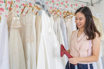 Asian dressmaker woman or wedding designer doing steaming dress in bridal boutique or Rental Shop. Startup successful small business owner,SME. entrepreneur business concept