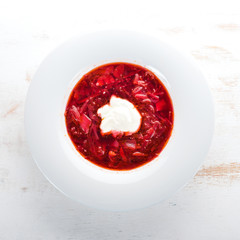 Vegetable beet soup. Borsch with sour cream. On the old wooden background. Free space for text. Top view.