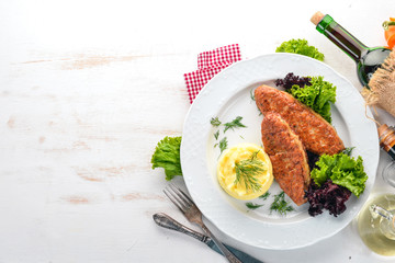 Cutlets of meat with mashed potatoes on a plate. On the old wooden background. Free space for text. Top view.