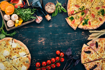 Background of Italian food. Assortment of pizza. On a black wooden background. Free space for text. Top view.