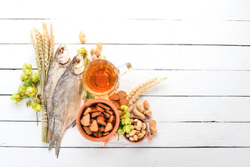 Background beer and snacks. Hops, beer, chips, nuts. On a white wooden background. Free space for text. Top view.