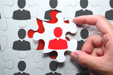 Selecting right people for organization's success. Think different and unique concept. Putting last jigsaw puzzle piece with red businessperson.