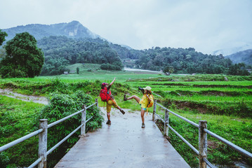 Fototapeta na wymiar Lover asian man asian women travel nature. Walking a photo the rice field and stop take a break relax on the bridge at ban mae klang luang in rainy season.