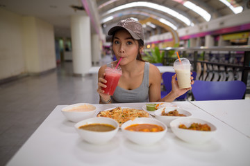 Young beautiful woman enjoying Indian food at restaurant