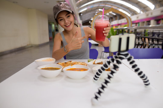 Young beautiful woman vlogging with mobile phone in restaurant