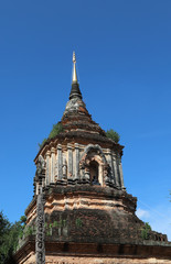 Fototapeta premium Scenery of vintage Buddhist pagoda and Buddha statue with clear blue sky background. Vertical view. 
