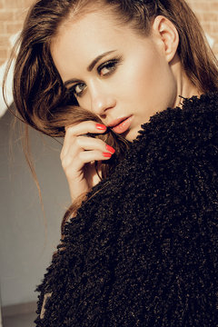 Gorgeous young model woman with perfect brunnete hair looking at camera posing in the city wearing black jacket on sunset.